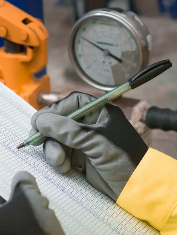 Inspector recording data on a clipboard in an industrial facility
